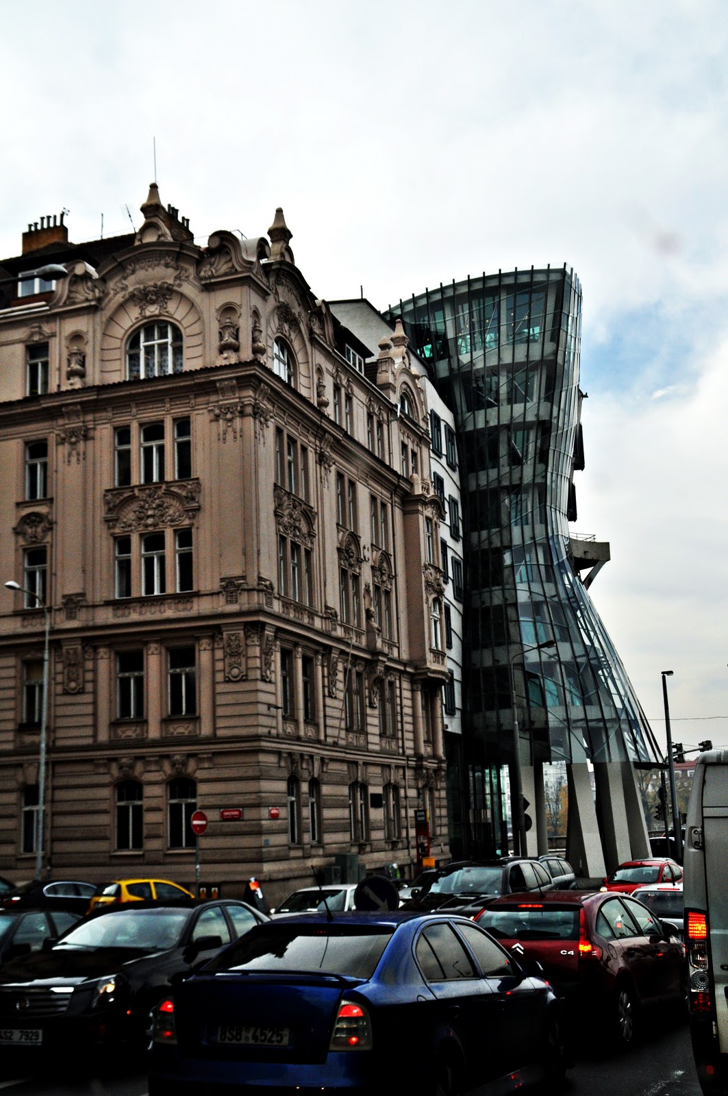 The curved glass and concrete Dancing House on the riverfront in Prague beside an older stone building