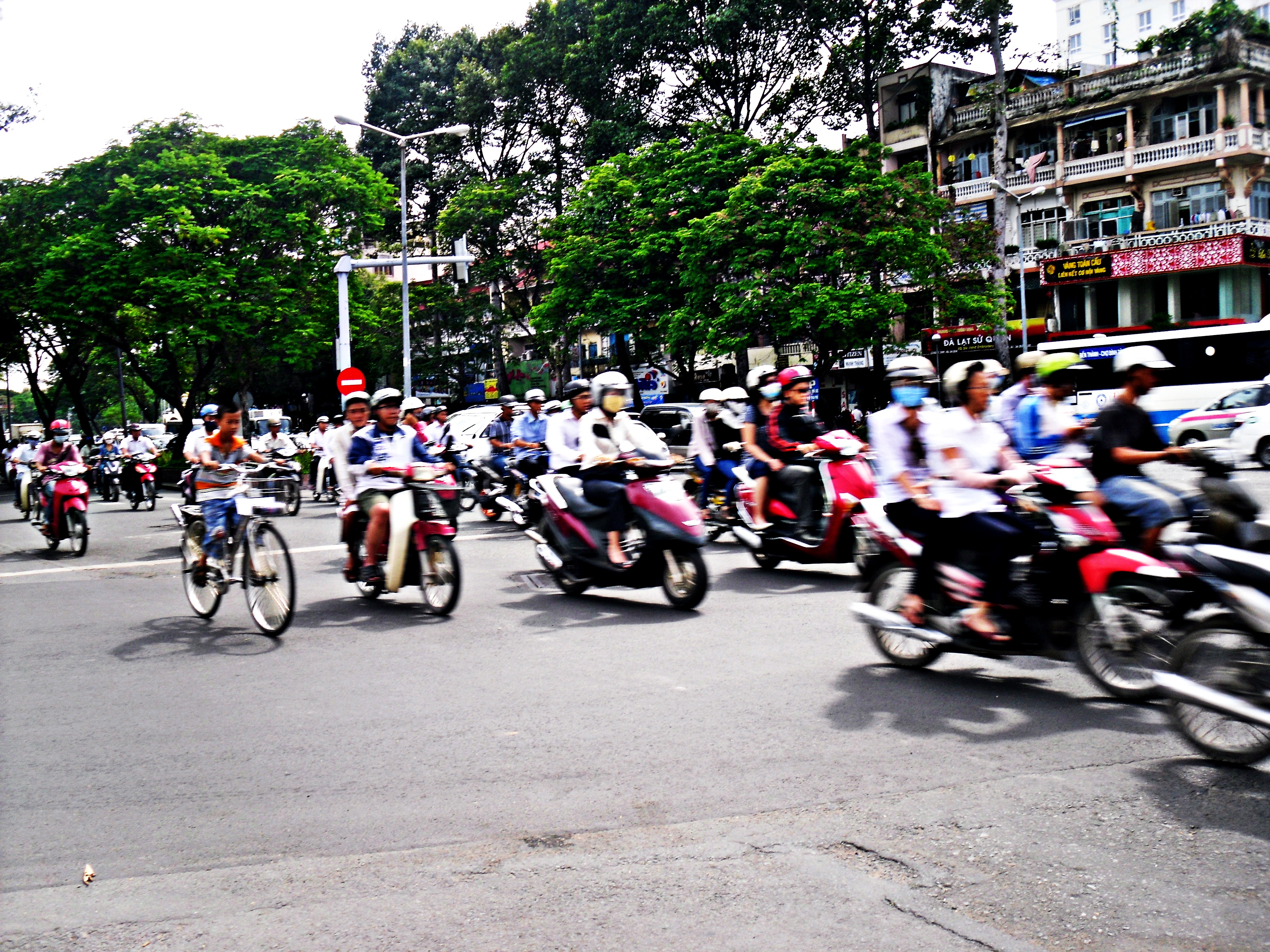 A wide Saigon street completely filled with motorbikes at a junction