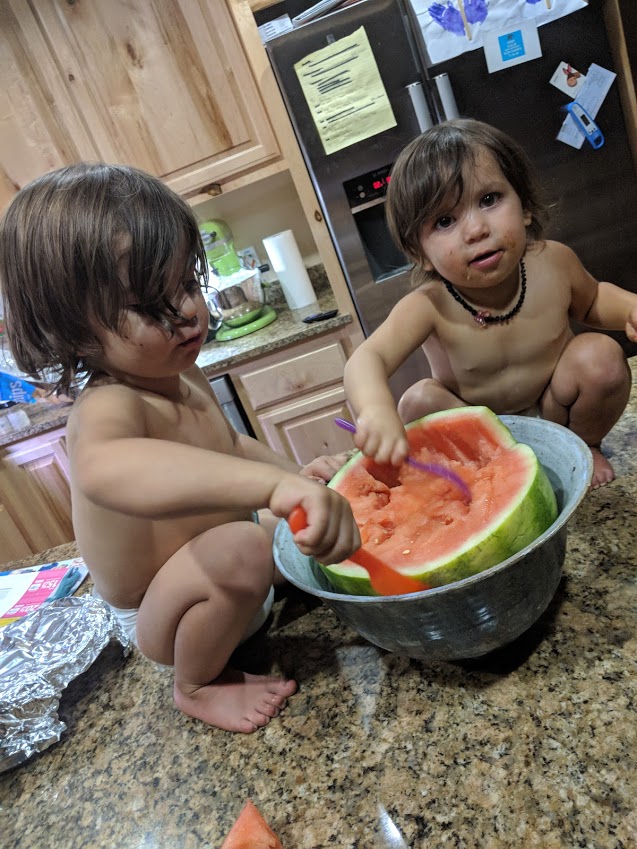 Two of the Damiano children sharing a watermelon on the kitchen counter