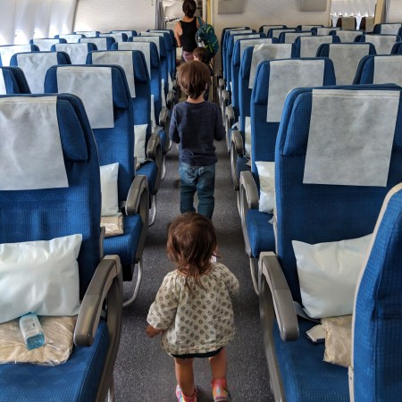 Nicole and two young kids walking down the aisle of an airplane heading to their next adventure — the Adventures We Seek family has always been moving toward something more.