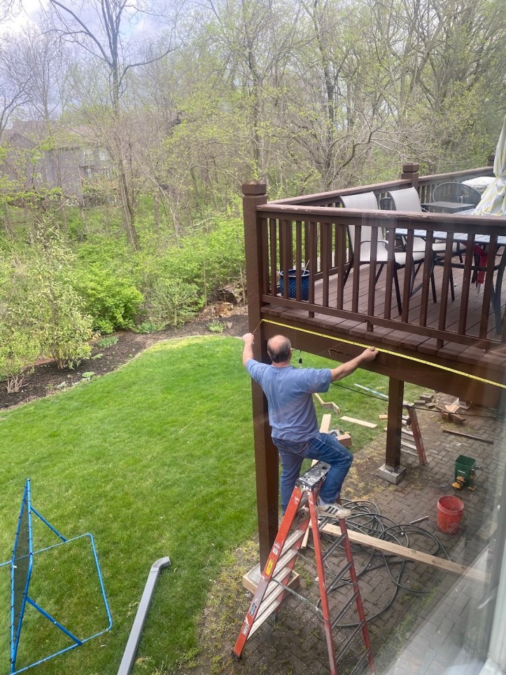 Contractor measuring and repairing the back deck of the Adventures We Seek family home in Kansas before it goes on the market for sale.