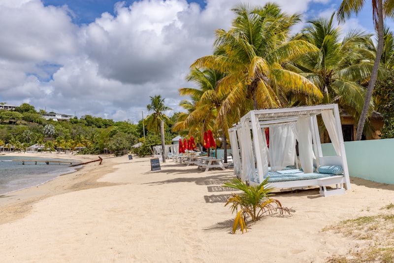 A beach with cabanas and pale blue water in Antigua