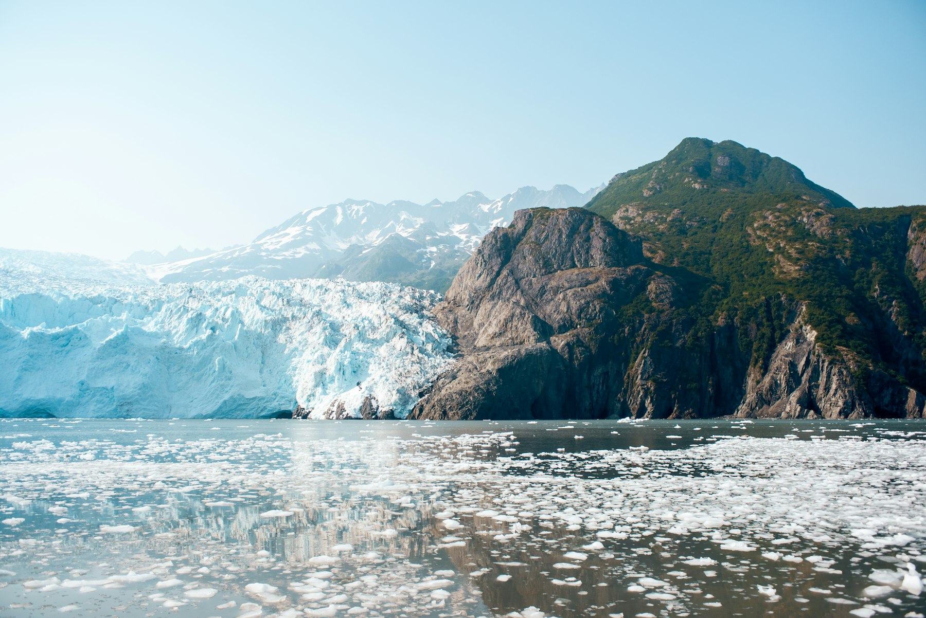 Floating ice in front of a tidewater glacier and a rocky headland in an Alaskan fjord