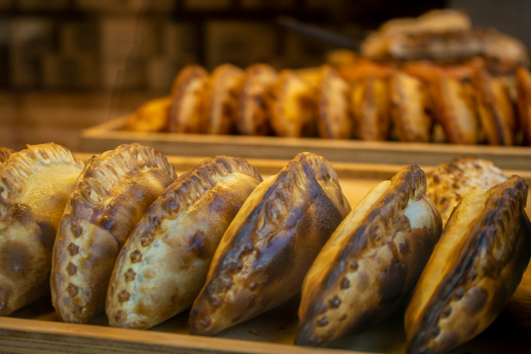 A tray of baked empanadas with crimped edges