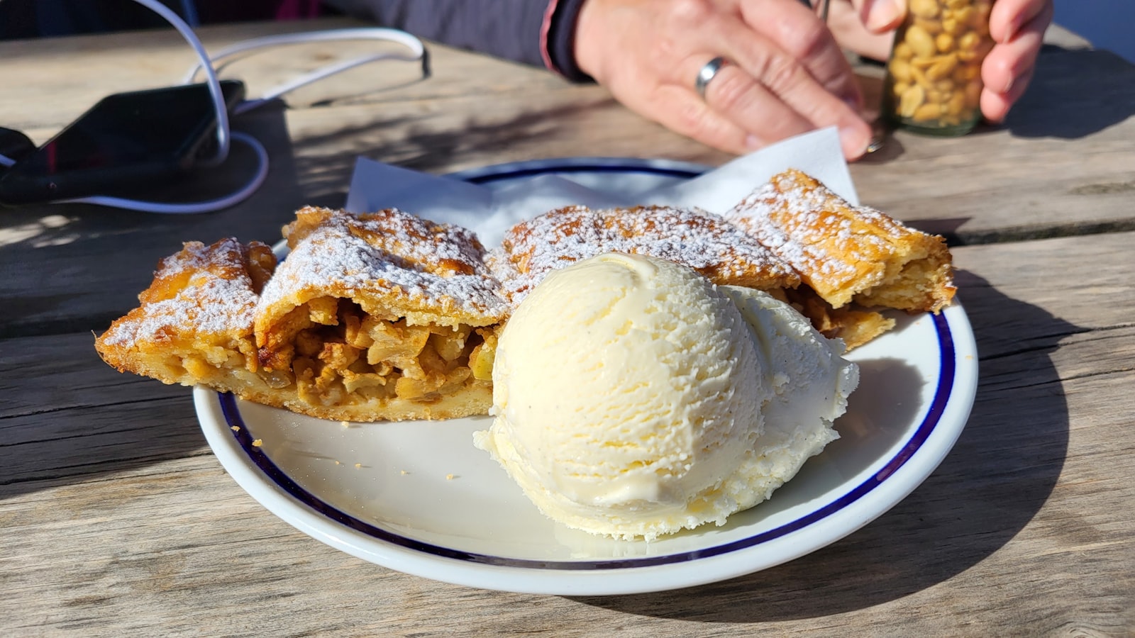 A slice of apple strudel served warm with a scoop of vanilla ice cream