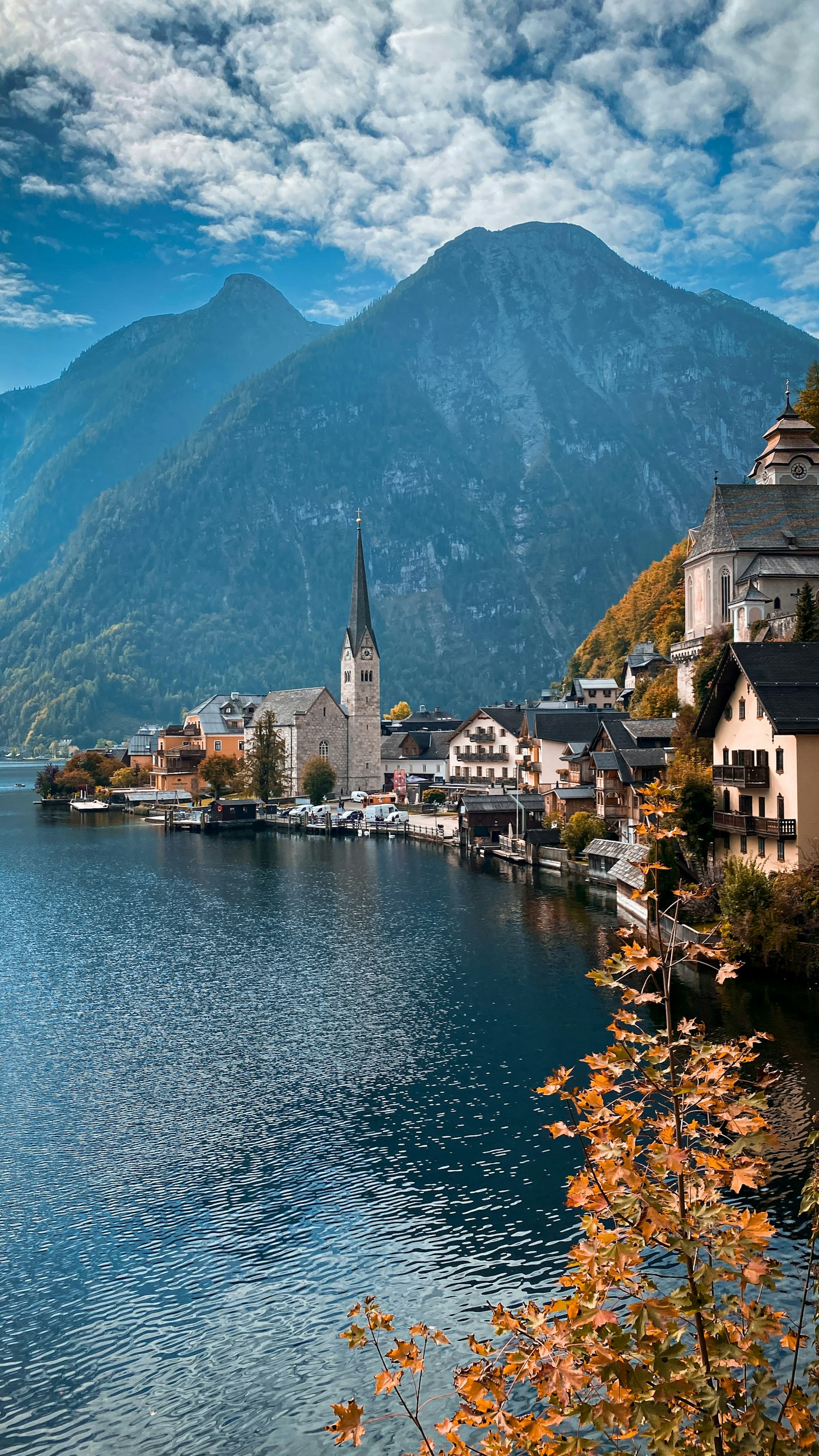 The church spire and lakeside houses of Hallstatt below a steep wooded mountain