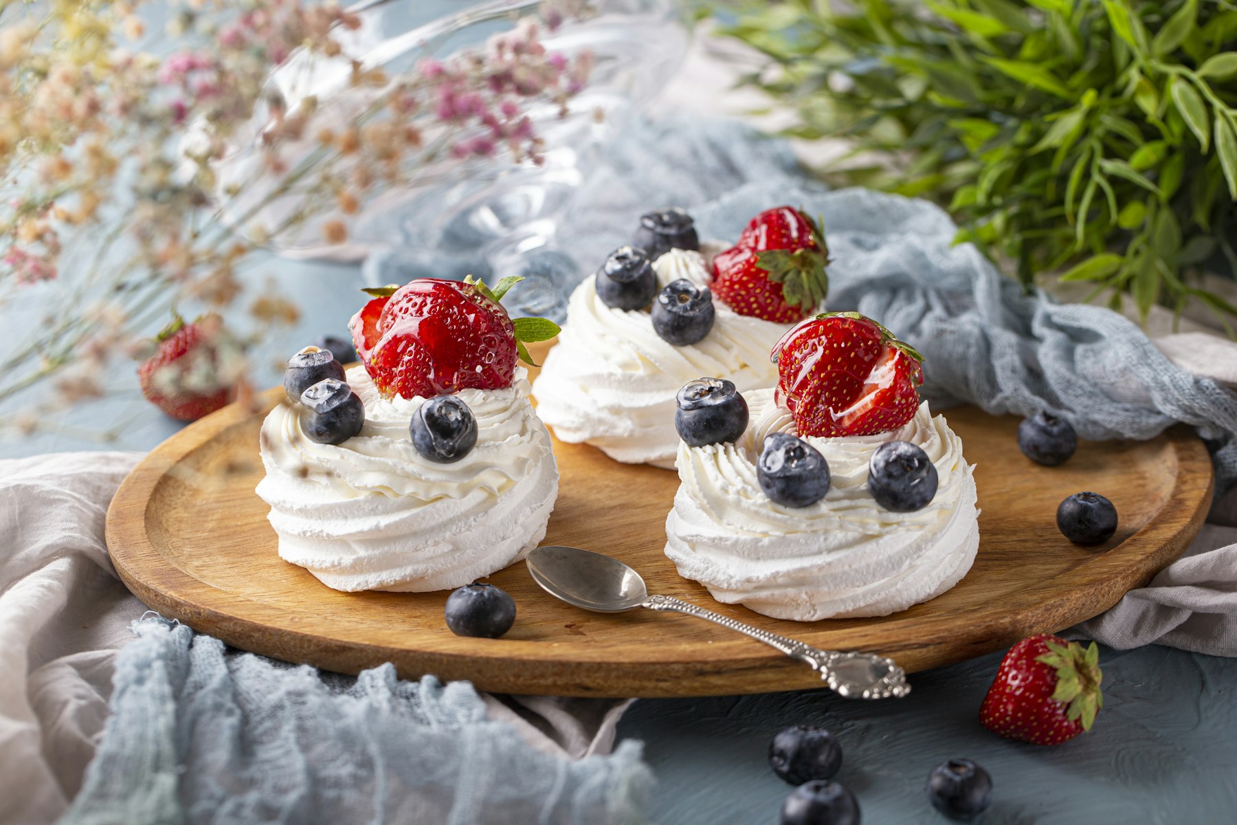 Two meringue pavlova desserts topped with cream and berries
