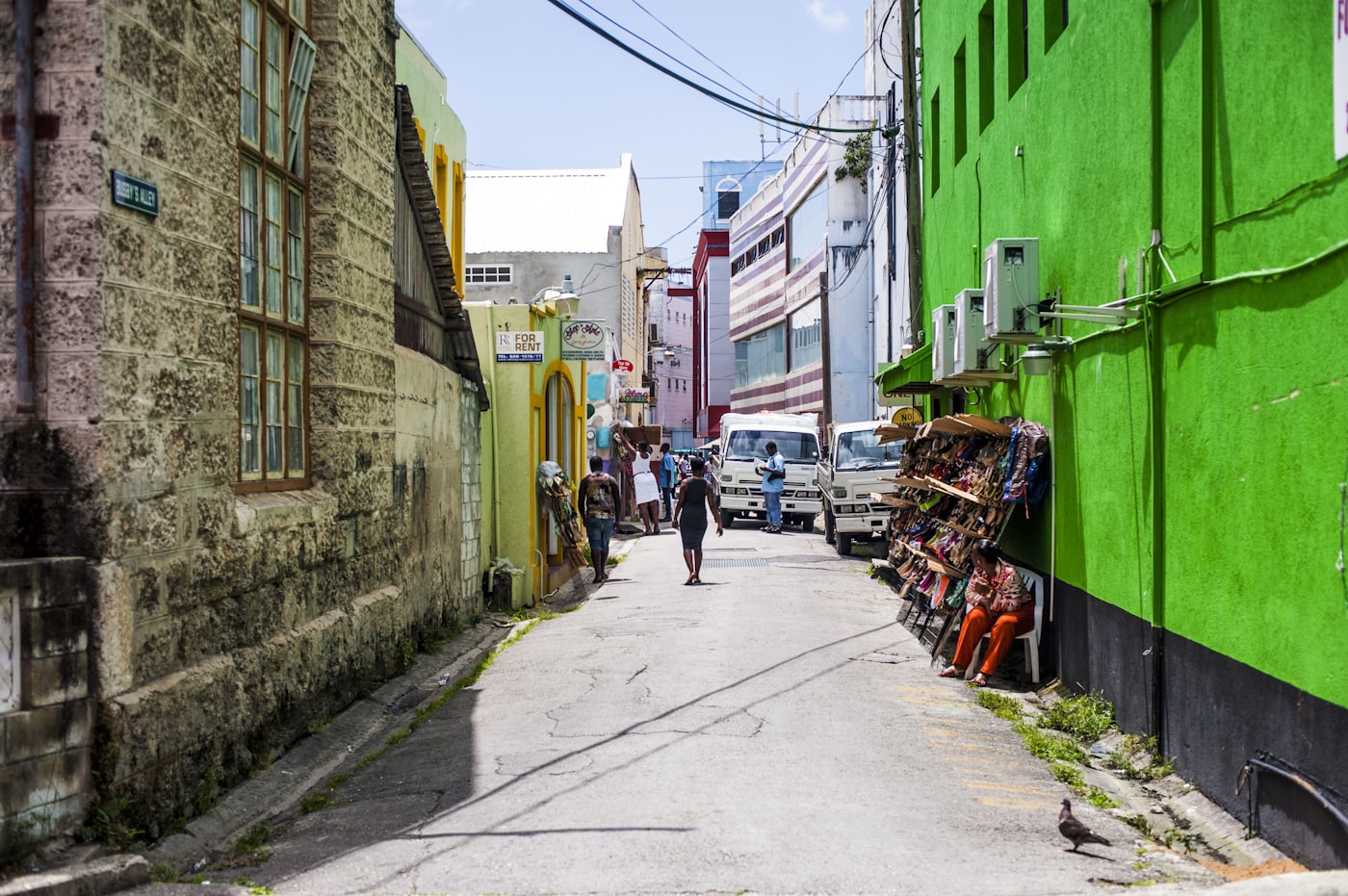 A man walking past a green painted shopfront on a street in Bridgetown, Barbados