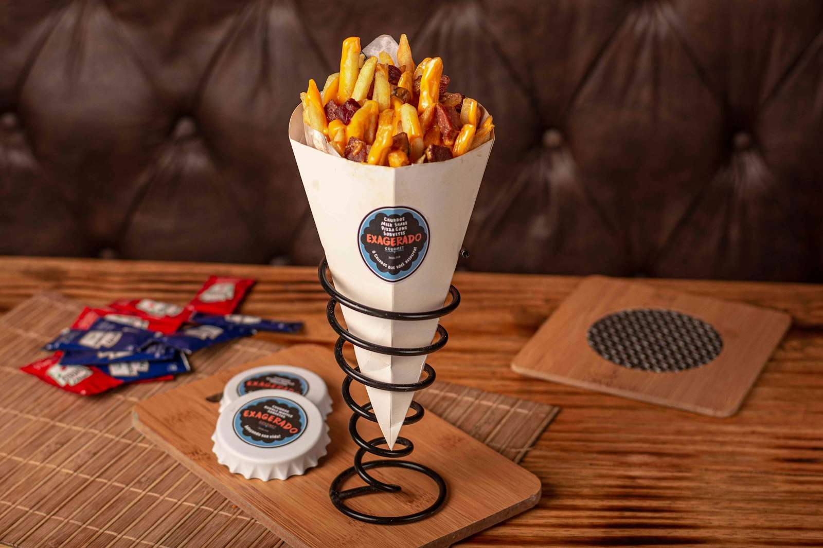 A paper cone of thick golden Belgian fries standing in a metal holder