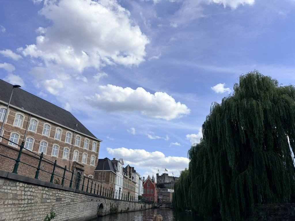 Old brick and stone houses lining a wide canal in Ghent on a summer afternoon