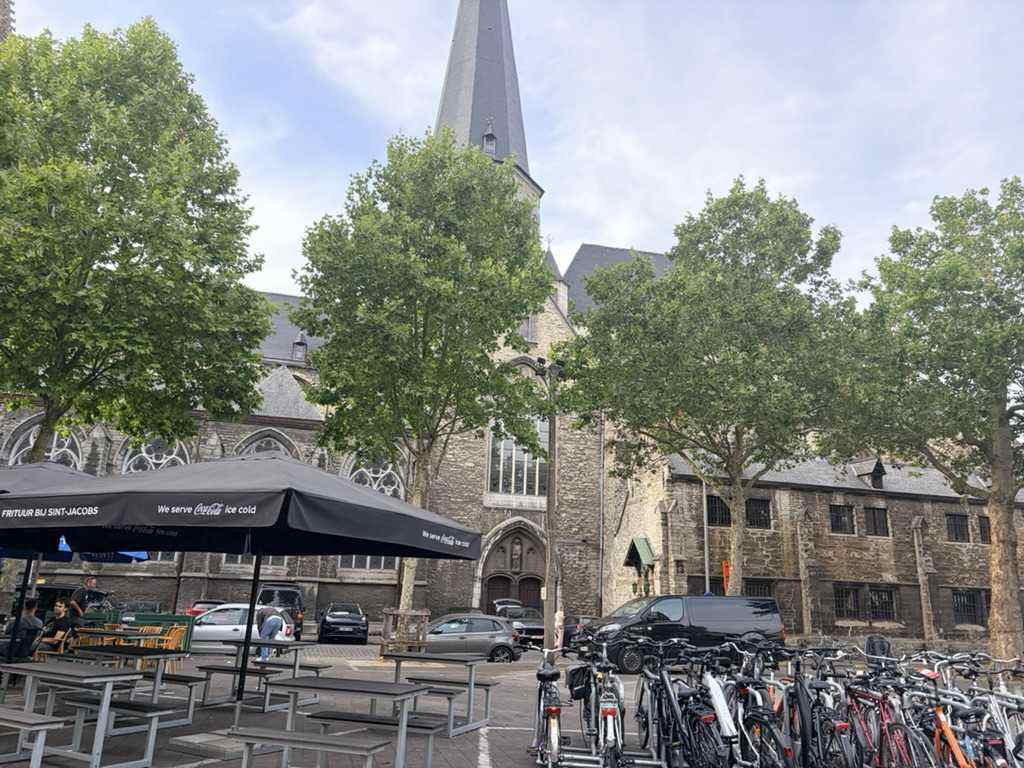 A church and cafe terrace on a Ghent square with rows of parked bicycles in front