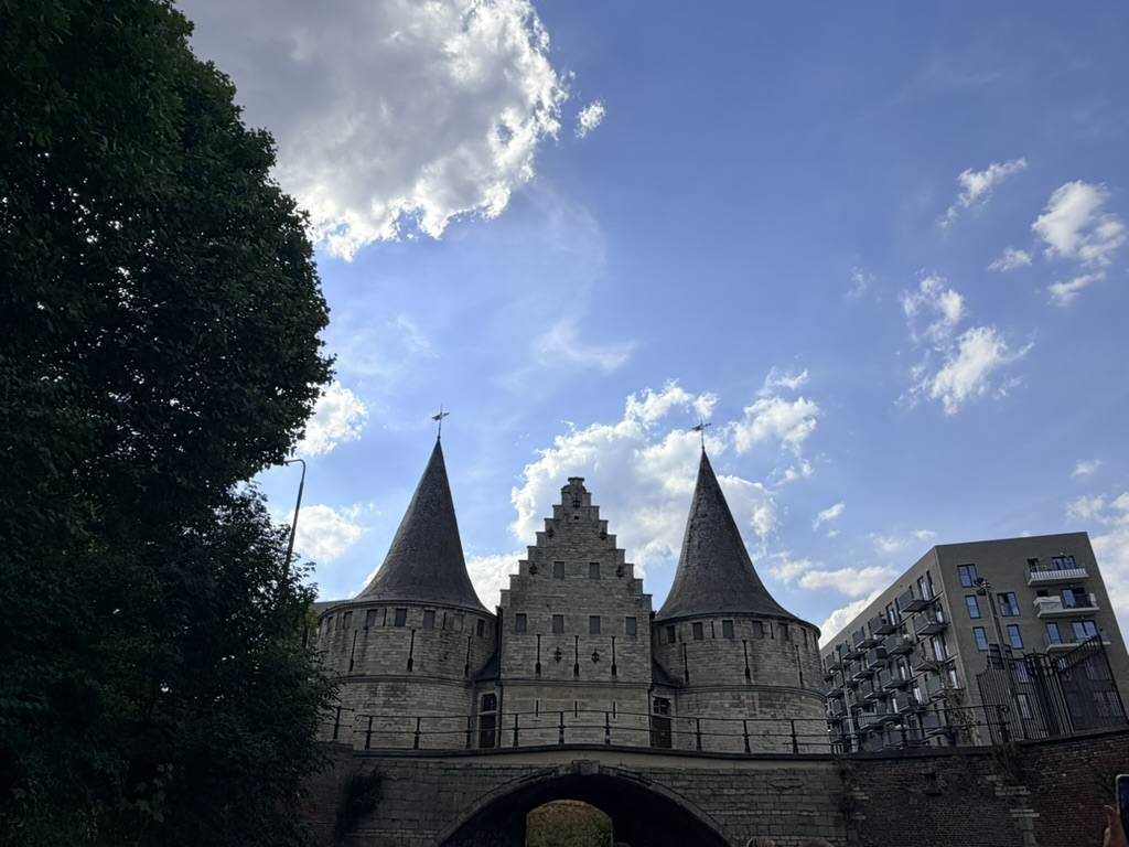 The three round stone towers of the Rabot water gate in Ghent against a blue summer sky