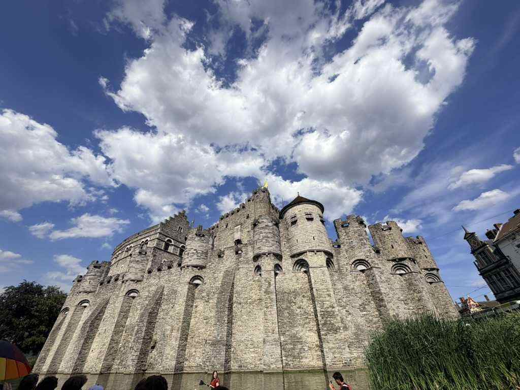 The grey stone walls and towers of Gravensteen castle in Ghent against broken cloud