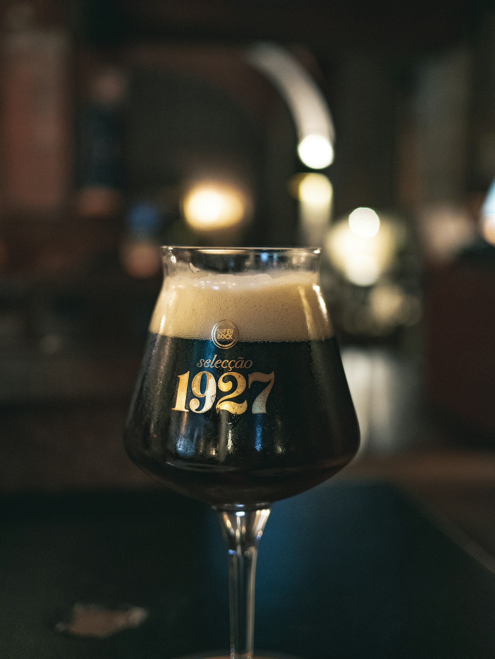 A dark Belgian Trappist beer in a stemmed glass on a bar