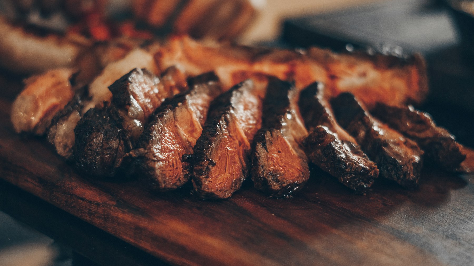 Sliced grilled picanha beef on a wooden board at a Brazilian churrasco