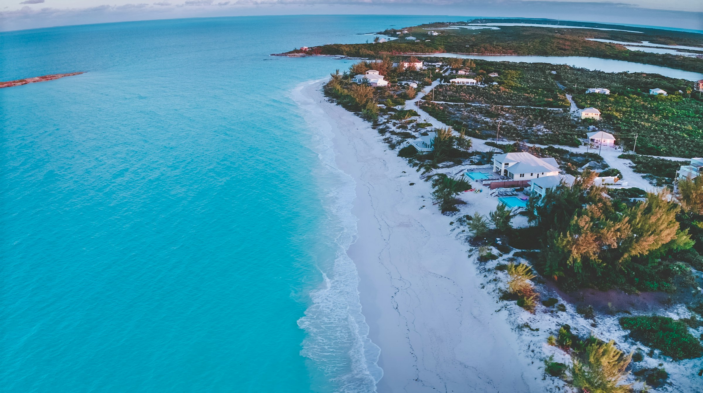 An aerial view of the empty white sand curve of Tropic of Cancer Beach in the Exumas