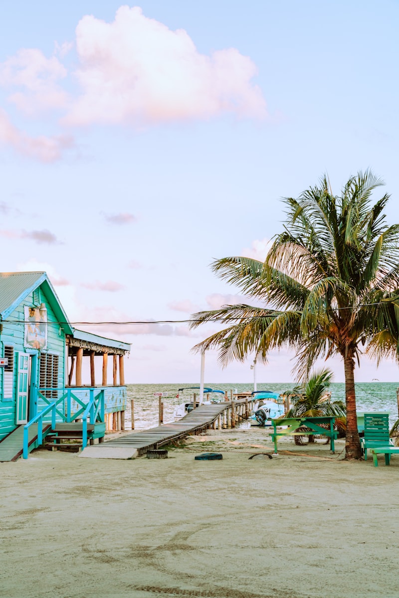 A blue wooden house on stilts beside the water on Caye Caulker, Belize