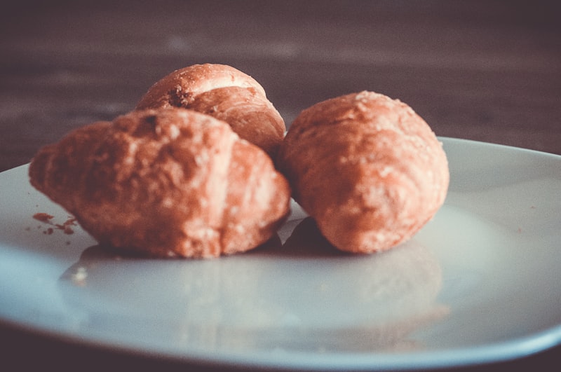 Three pieces of puffed fried dough on a white ceramic plate