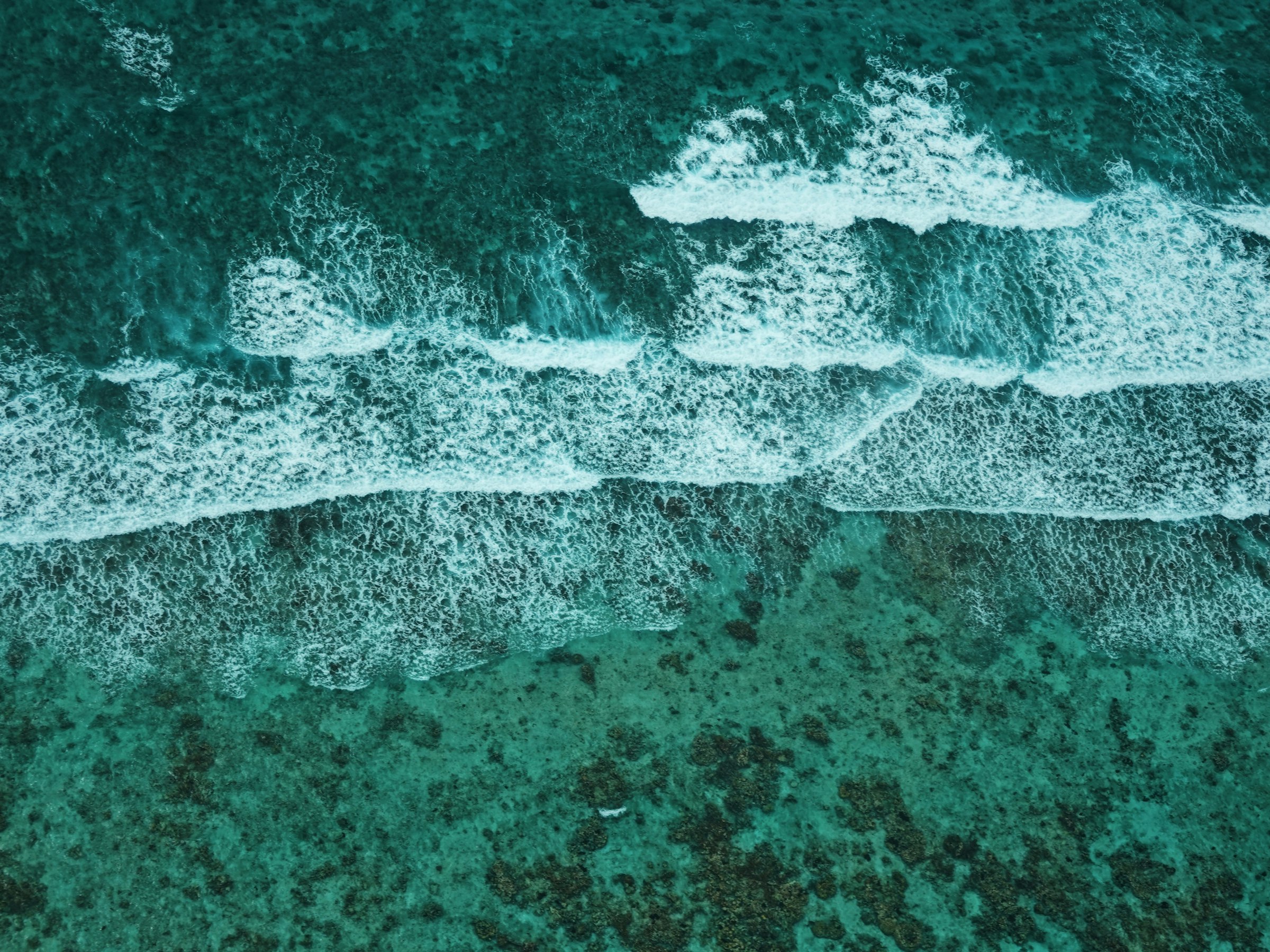 An aerial view of turquoise water breaking white over the Belize Barrier Reef off San Pedro