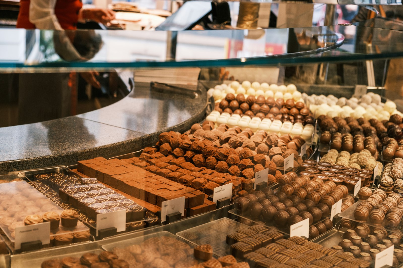Rows of handmade chocolates in a glass display case in a Swiss chocolate shop