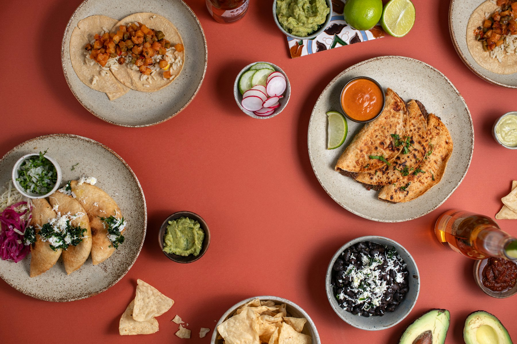 A spread of Mexican dishes and salsas laid out on a terracotta table