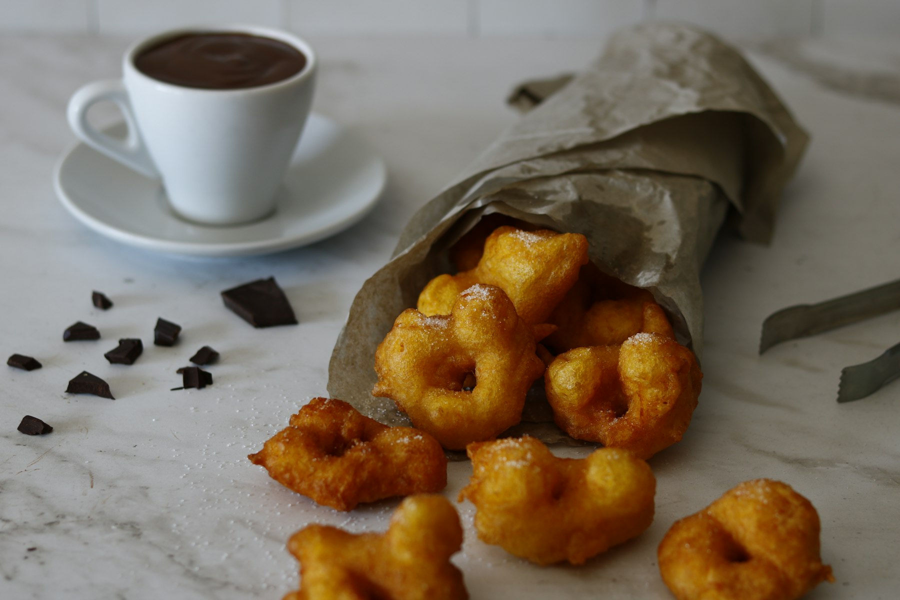 Fried Colombian bunuelos dough balls beside a cup of black coffee