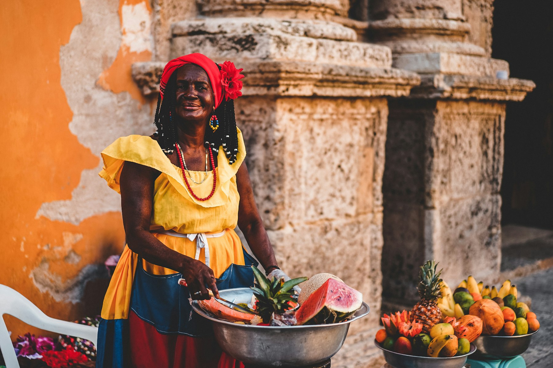 A palenquera fruit seller in Cartagena Colombia carrying a bowl of tropical fruit