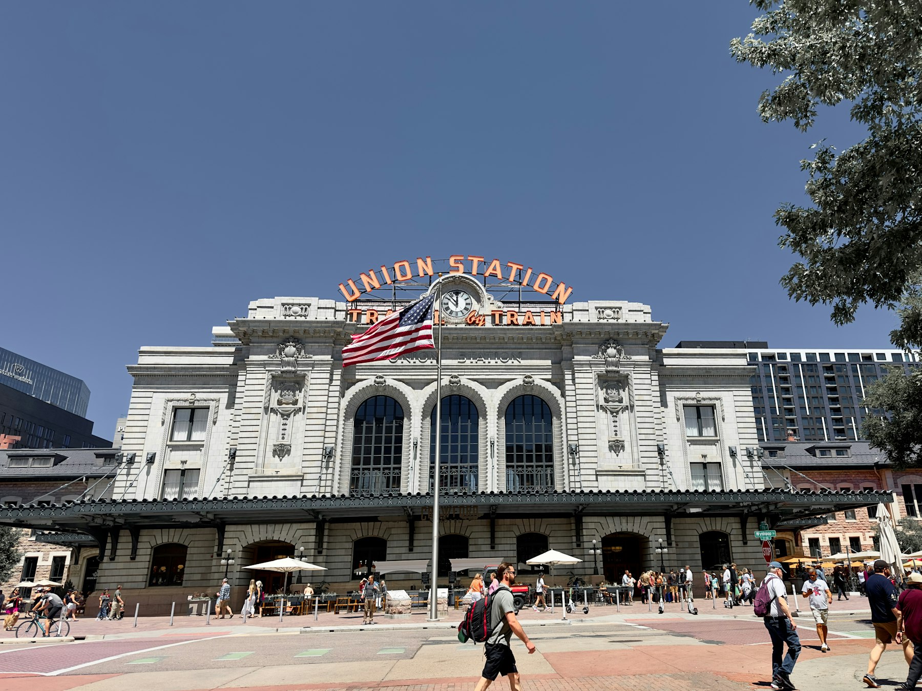 The facade of Denver Union Station with people walking in the plaza in front