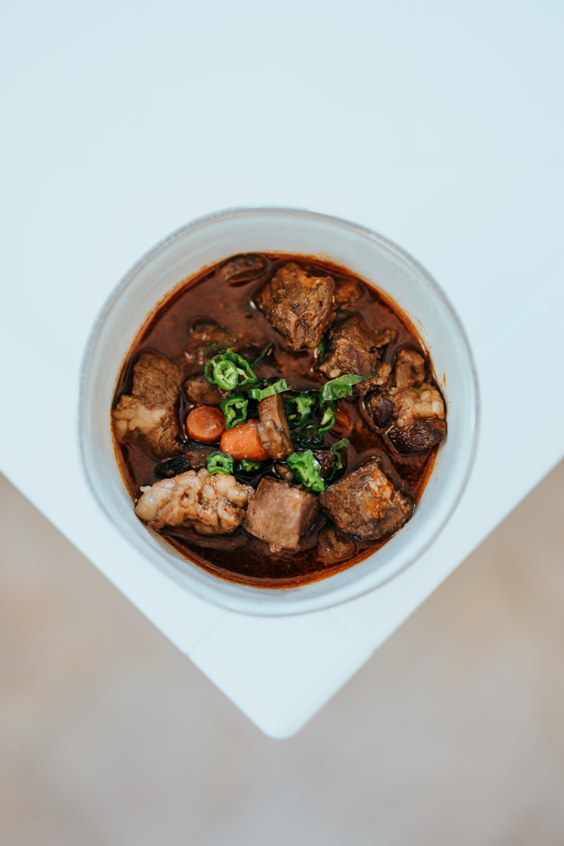 A white ceramic bowl of slow cooked meat stew