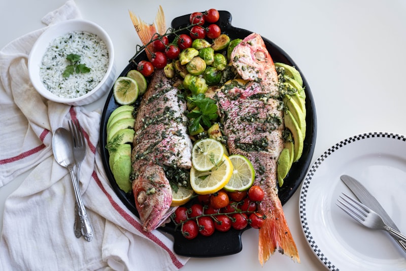 A platter of cooked fish with tomatoes and cucumber
