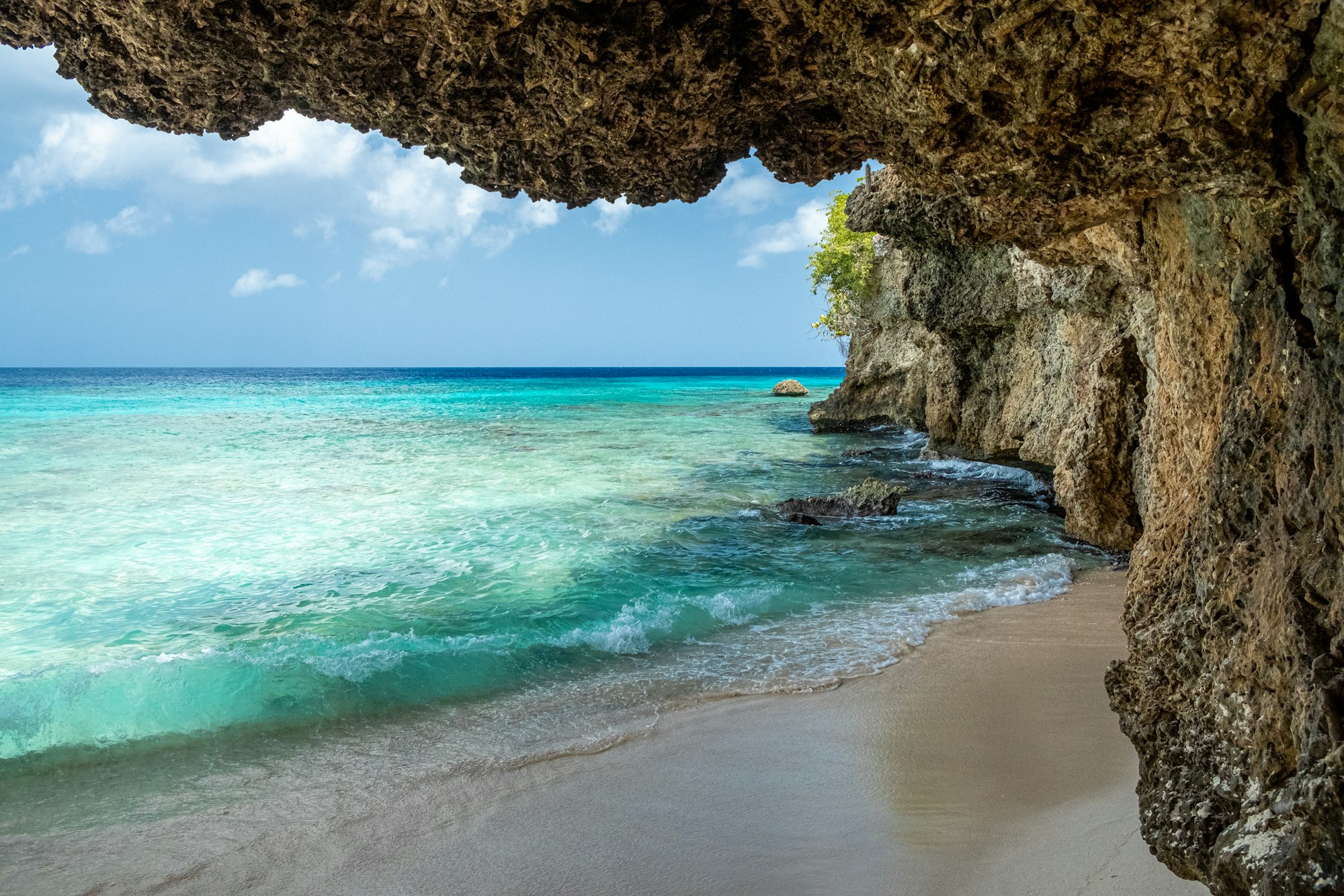 A brown rock formation beside clear water on the coast of Curacao