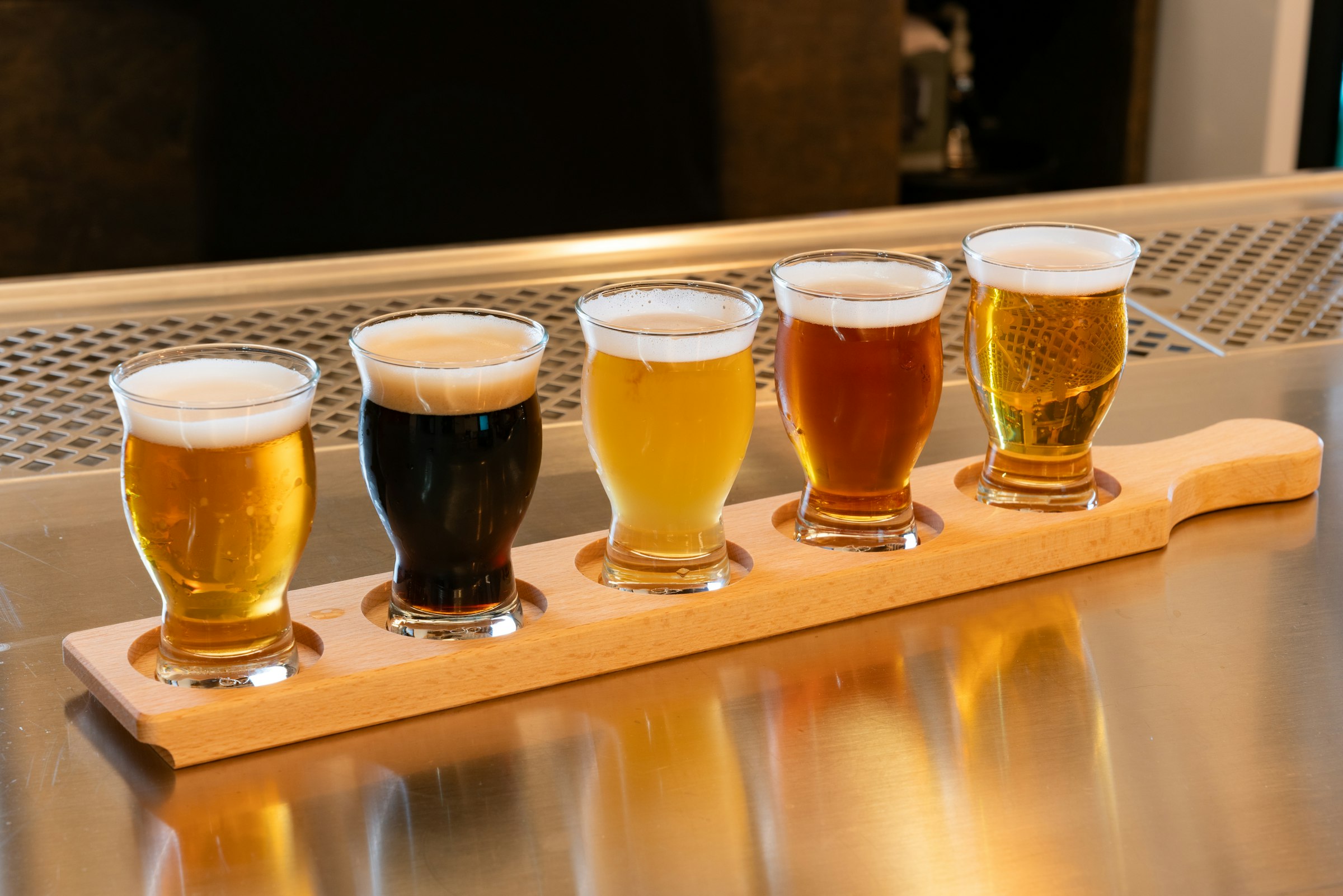 A wooden paddle of five Czech beers from pale lager to dark on a bar in Prague