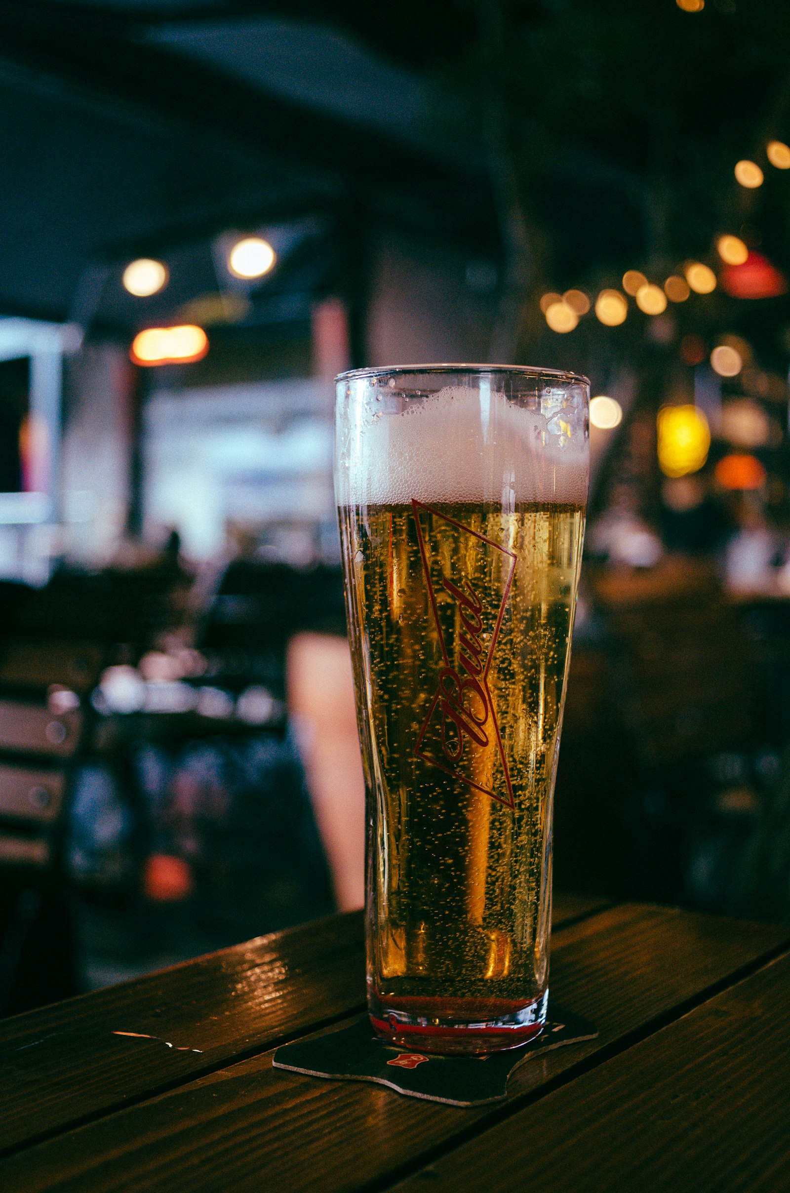 A tall glass of pale Czech lager with a thick head on a pub table