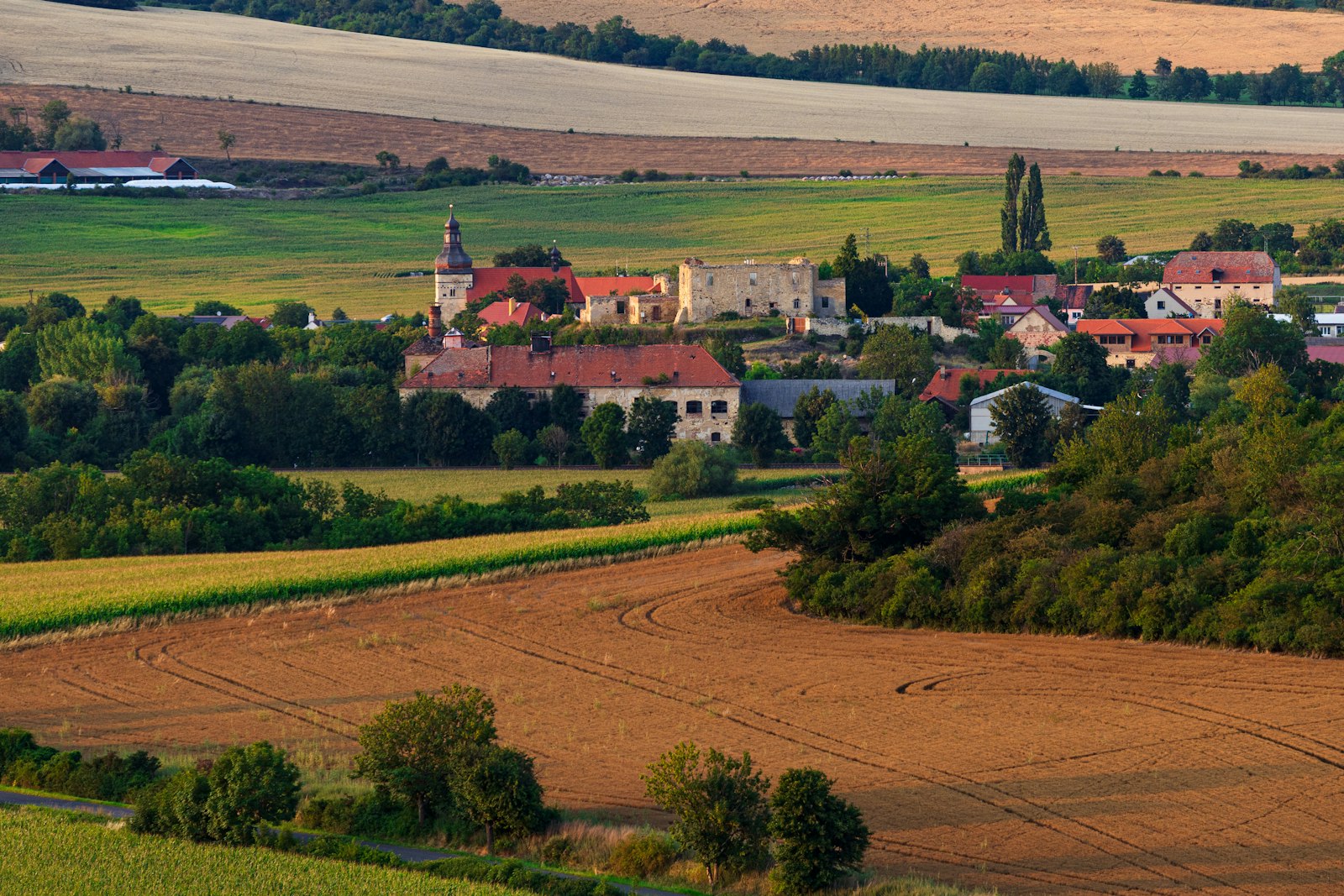 Rolling farmland and a small red roofed village in the Czech countryside