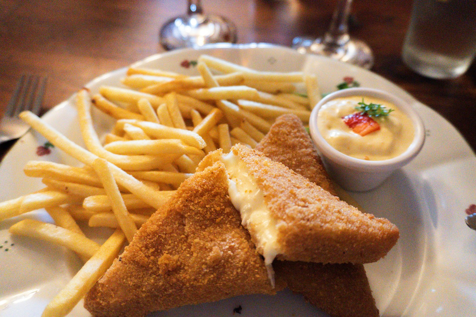 A slab of breaded fried cheese served with french fries and tartar sauce