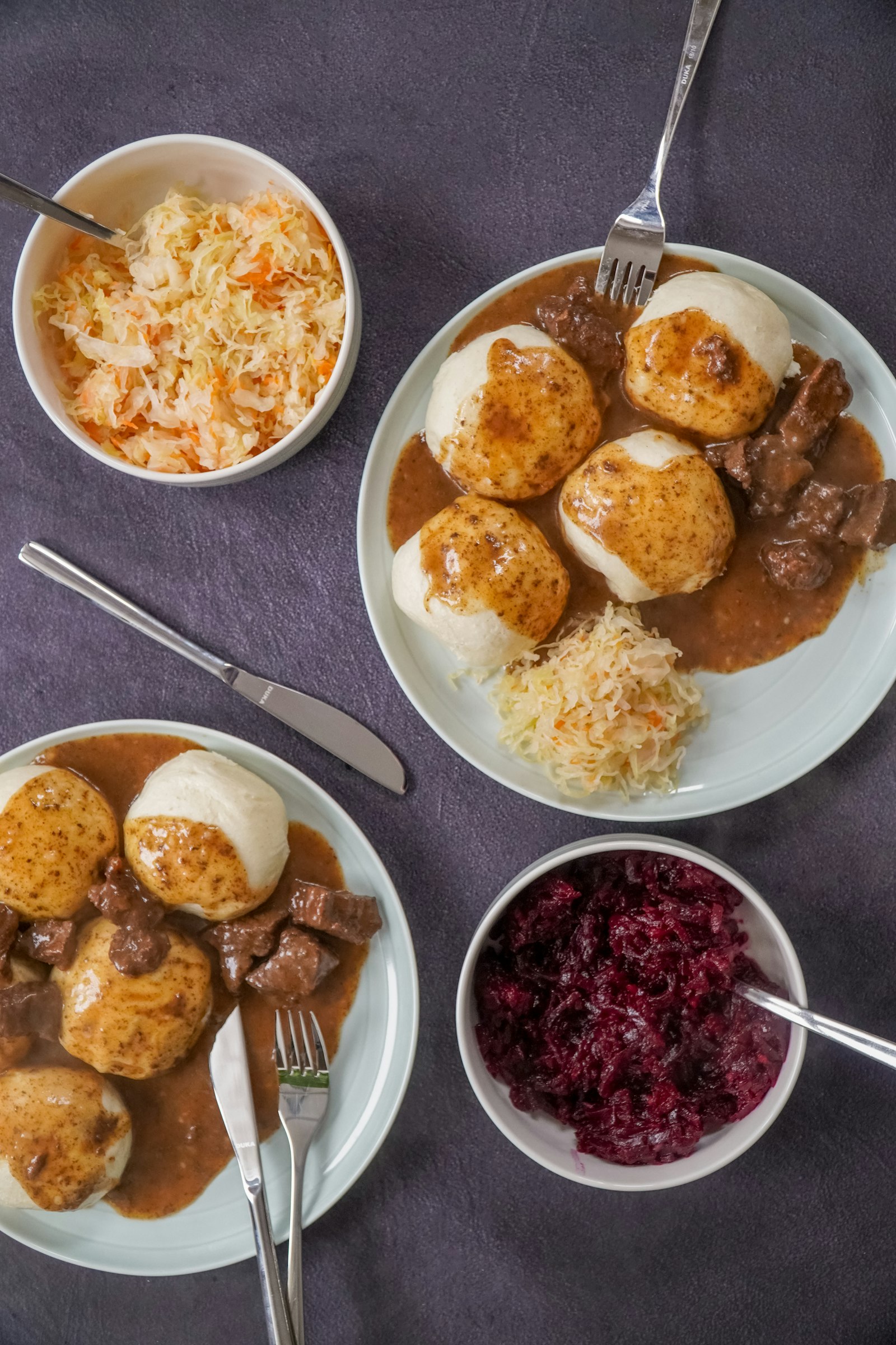 Roast pork with sliced bread dumplings and red cabbage in small bowls