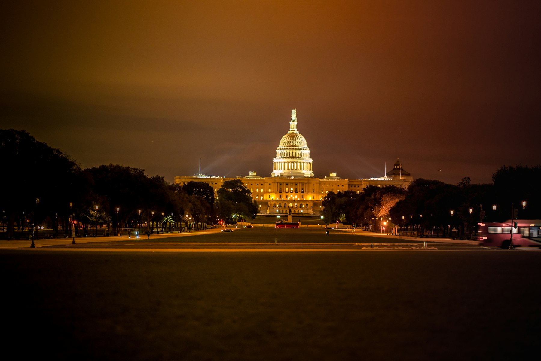 The floodlit dome of the United States Capitol at night seen down the length of the National Mall