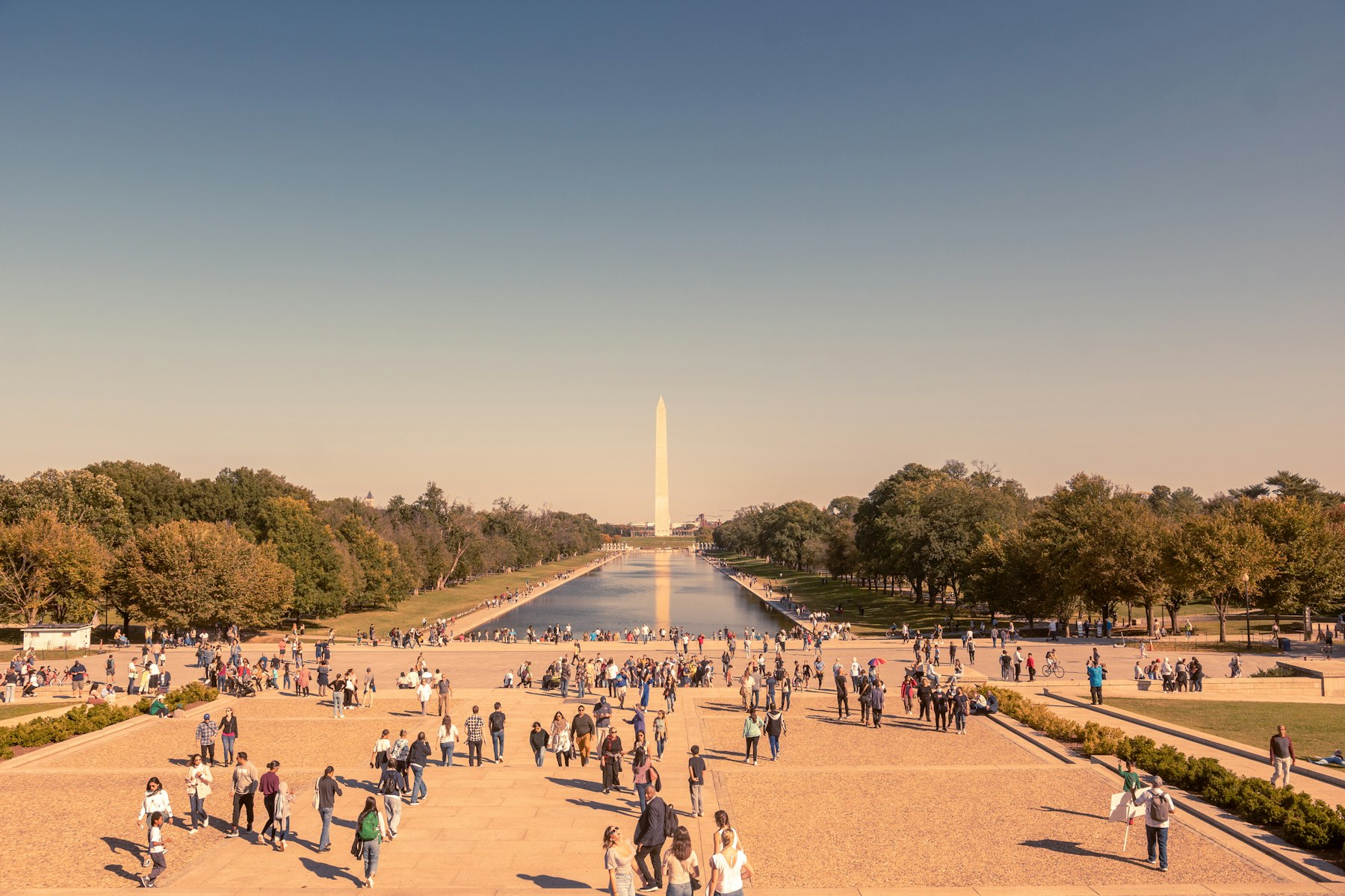Crowds walking beside the Reflecting Pool on the National Mall with the Washington Monument behind