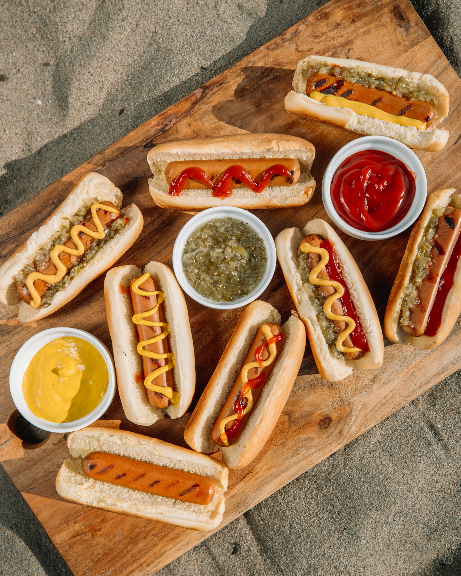 Danish hot dogs with mustard, remoulade and pickled cucumber on a wooden board