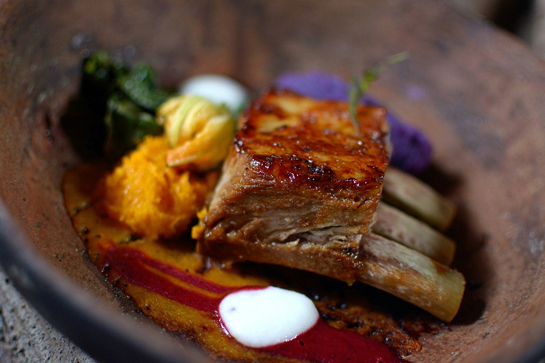Slow roasted pork served with a puree in a dark bowl