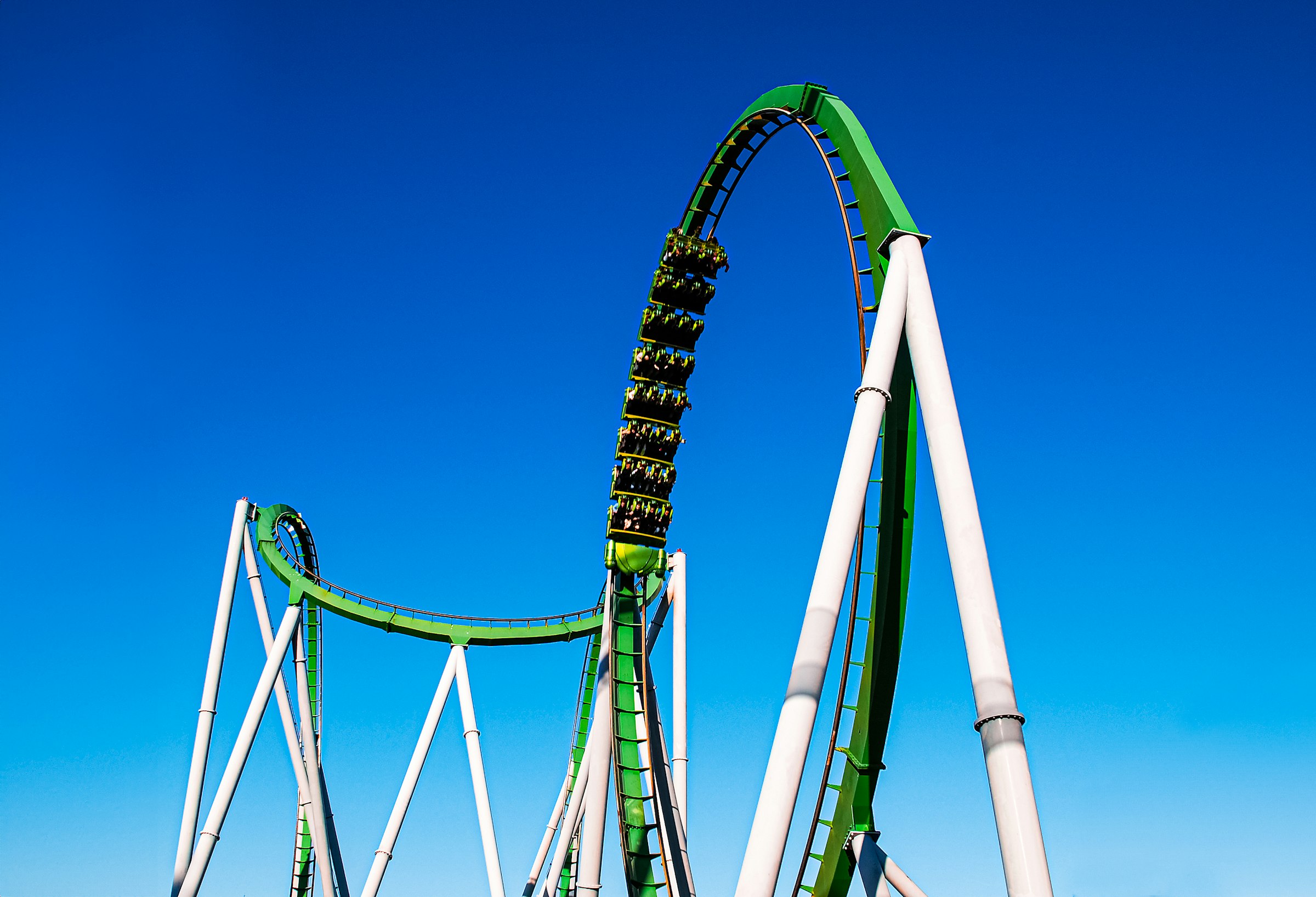 A green and white steel roller coaster track against a blue sky at a Florida theme park