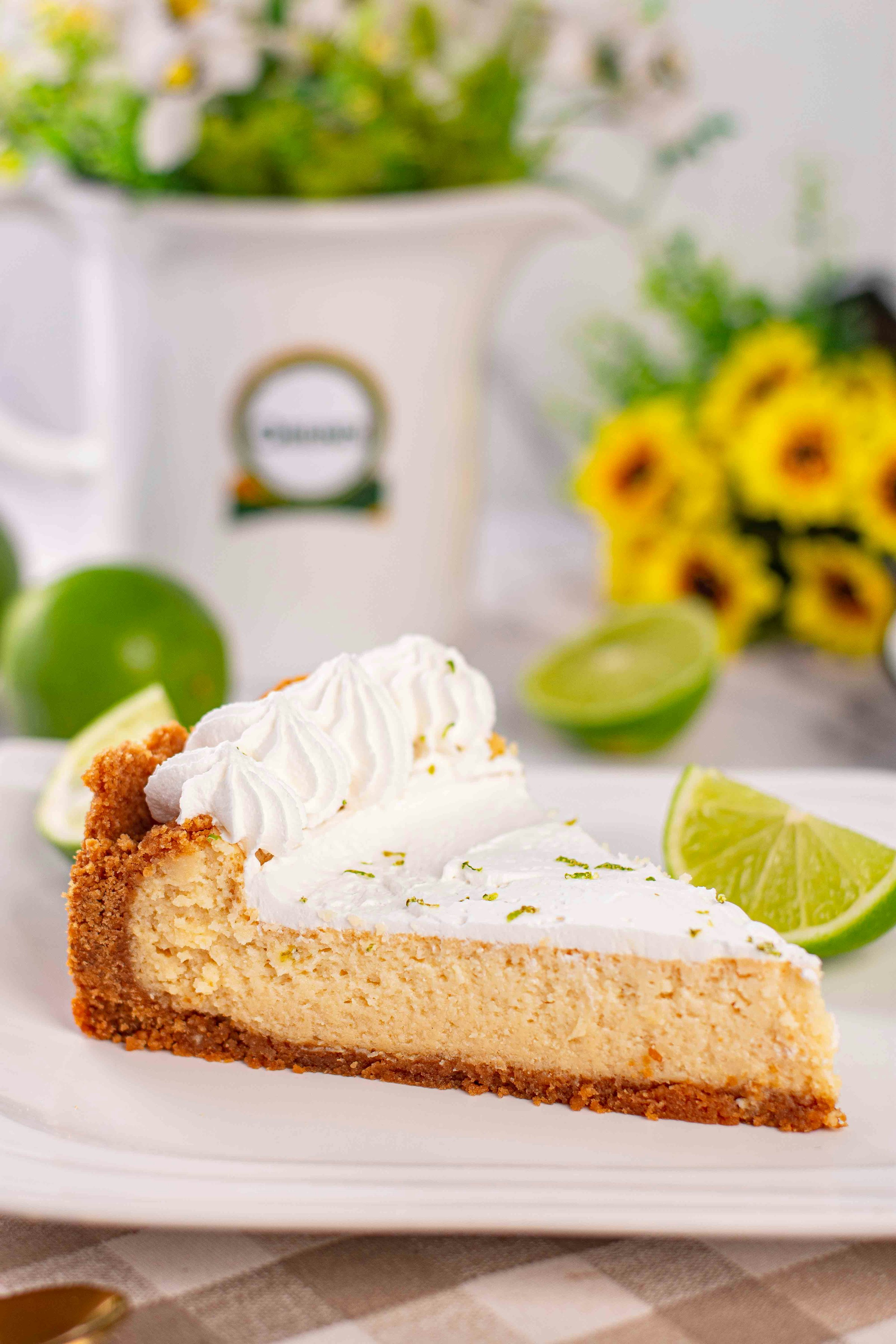 A slice of key lime pie topped with whipped cream and lime on a plate