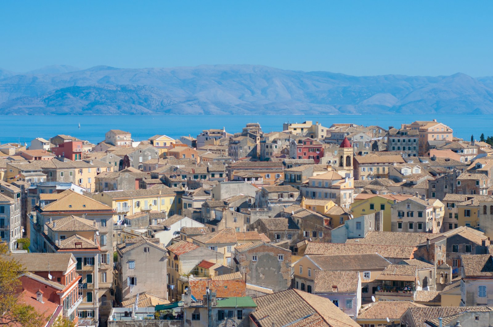 The terracotta rooftops of Corfu old town with the sea and mountains beyond