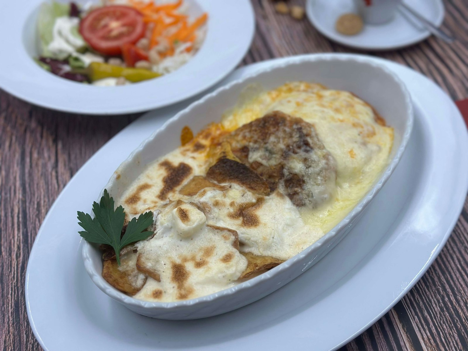 A baked dish of moussaka with aubergine and browned bechamel in a white oval dish