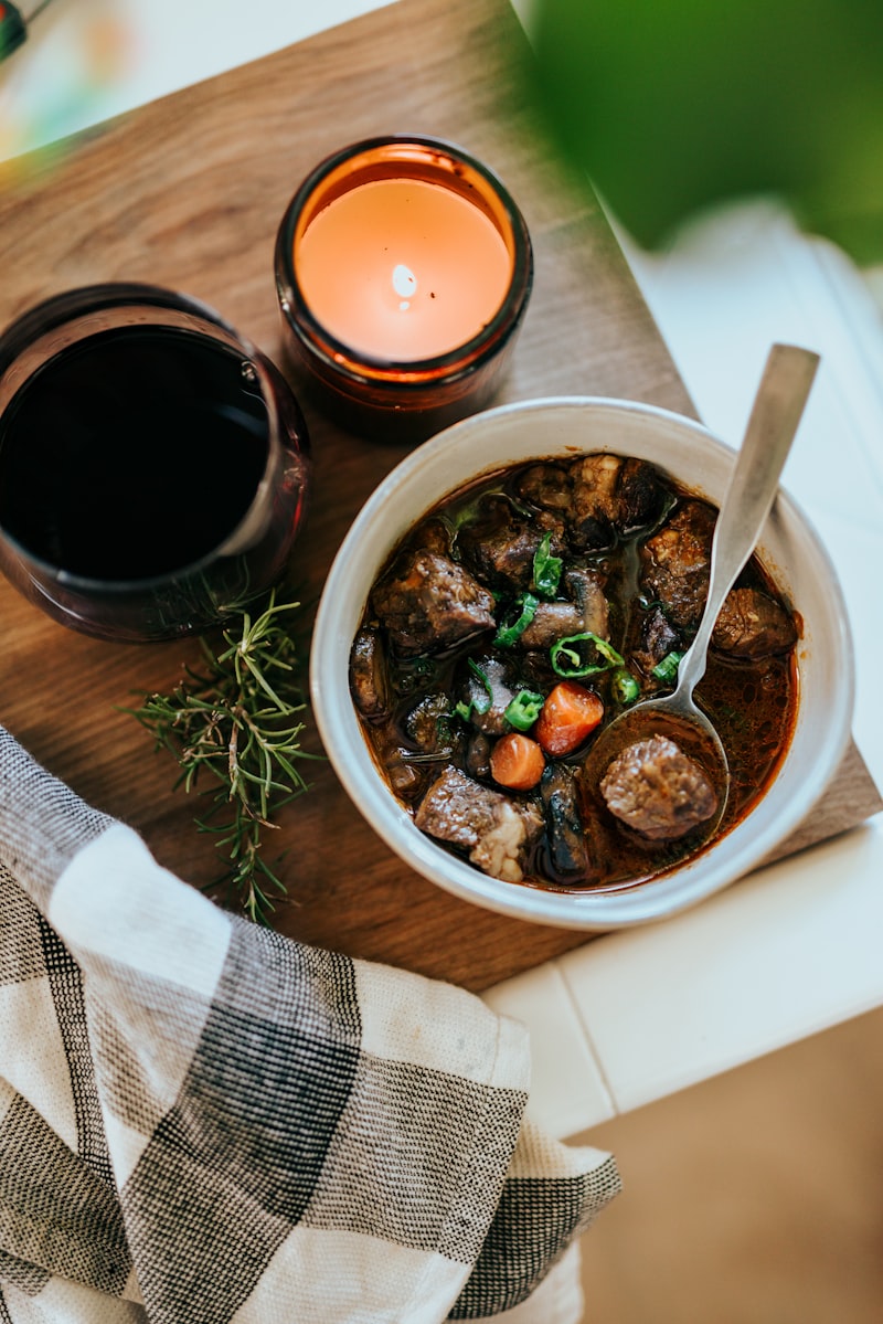 A white bowl of meat stew with herbs and a spoon