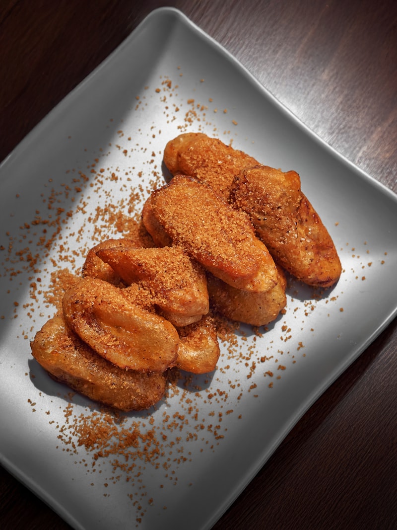 Golden fried dough pieces dusted with sugar on a white plate