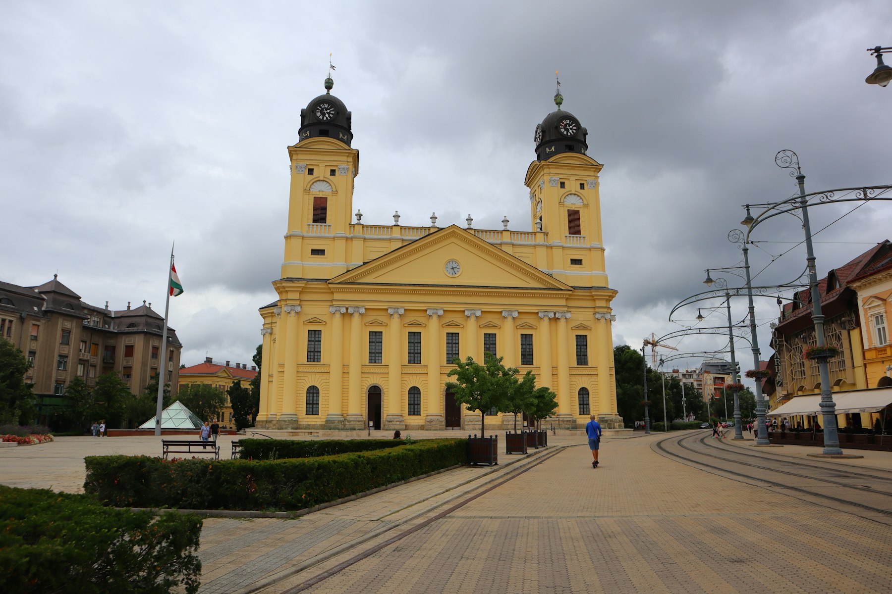The yellow twin towered Great Reformed Church of Debrecen at the end of a wide empty square