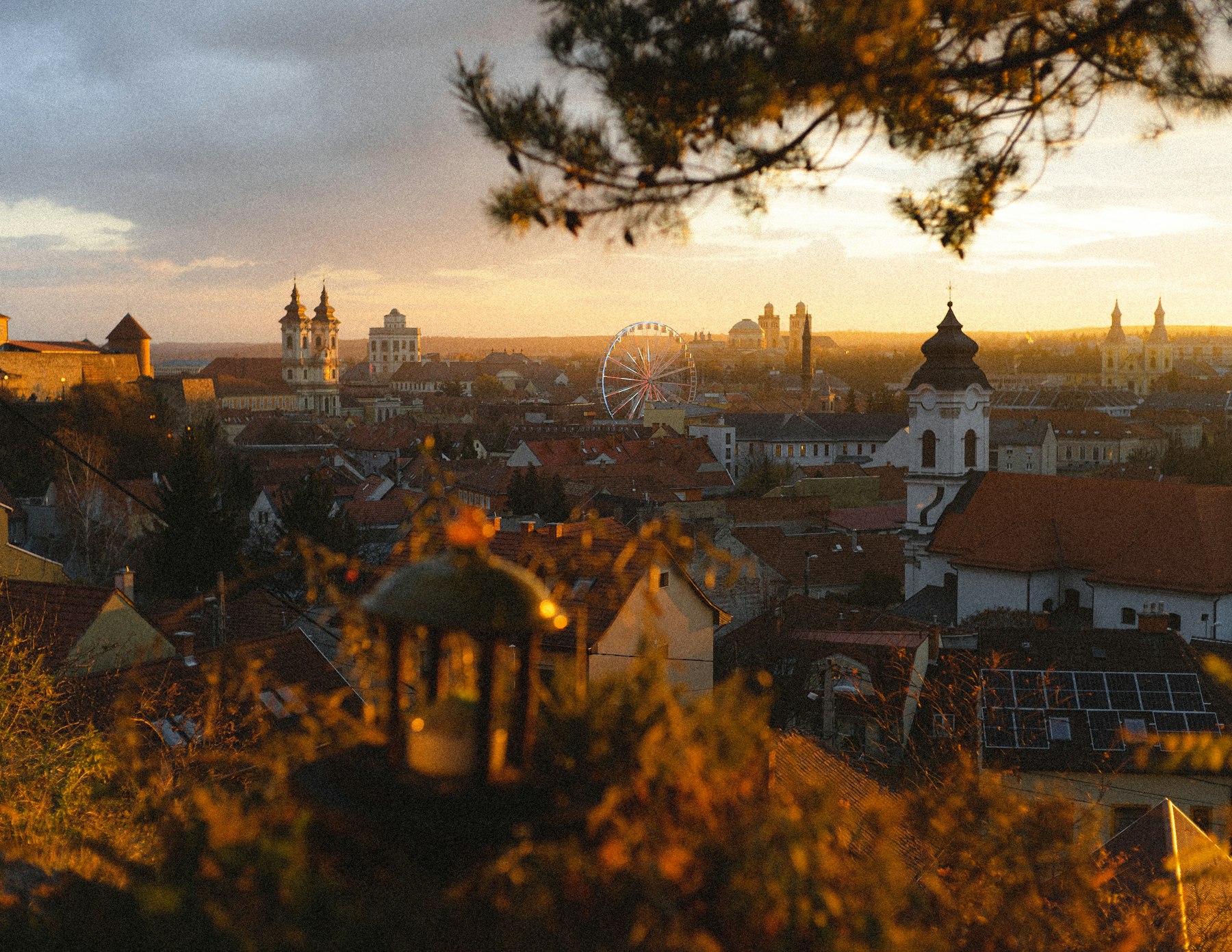 The baroque rooftops and church towers of Eger in Hungary glowing gold at sunset with hills behind