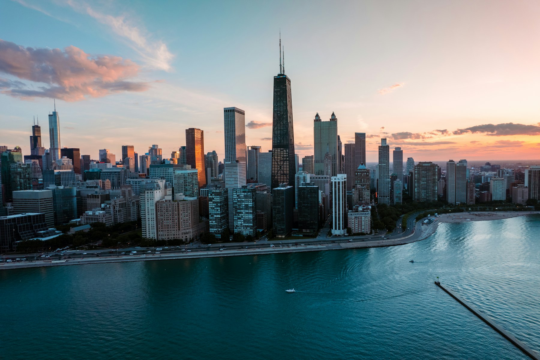 An aerial view of the Chicago skyline curving along the Lake Michigan shoreline at sunset