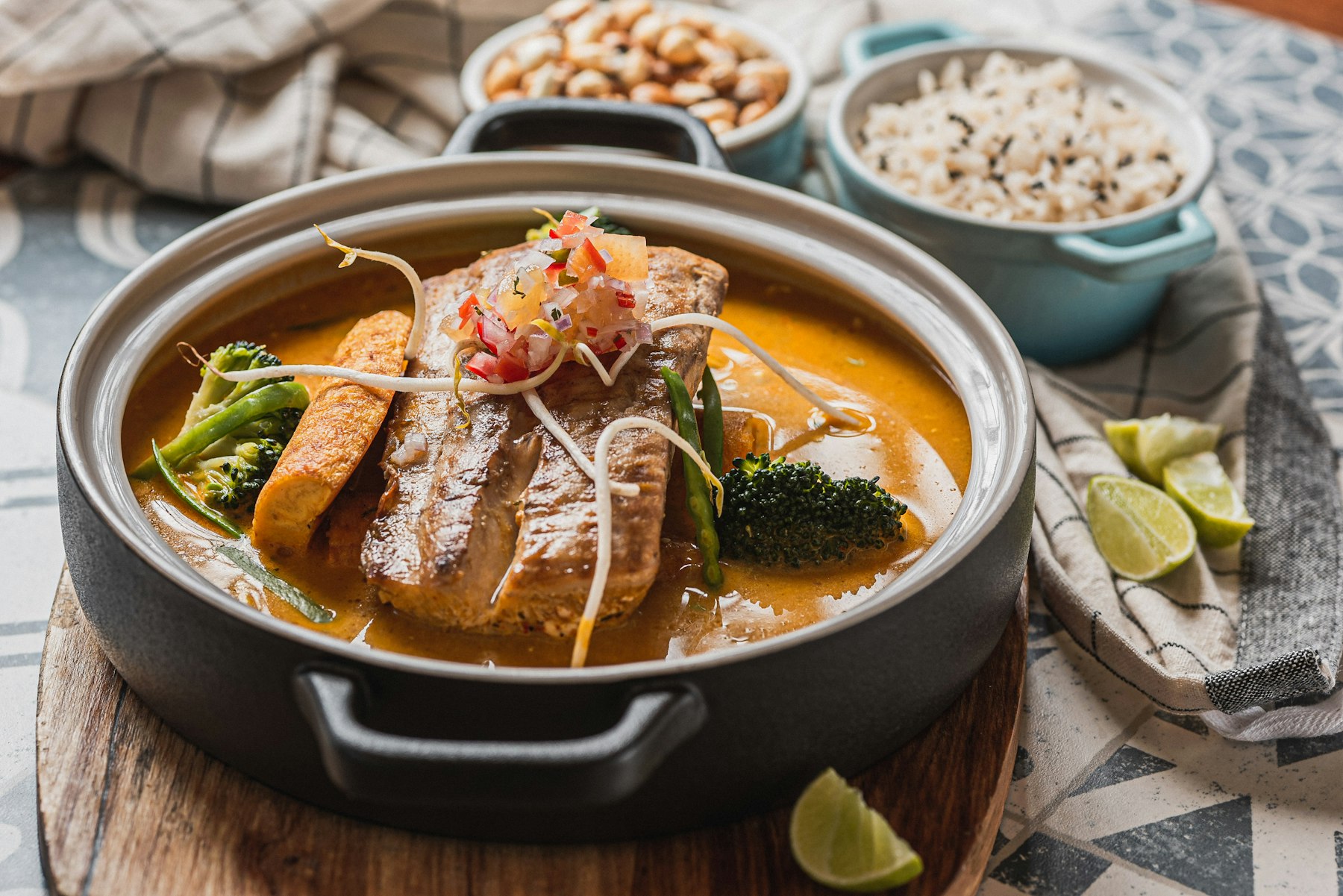 A pot of Cambodian fish amok, a thick coconut and lemongrass curry, served with rice and lime